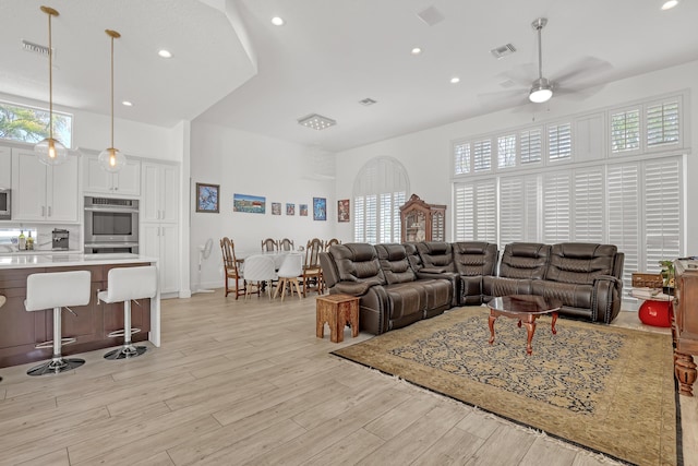 living area featuring light wood-style flooring, a healthy amount of sunlight, visible vents, and ceiling fan