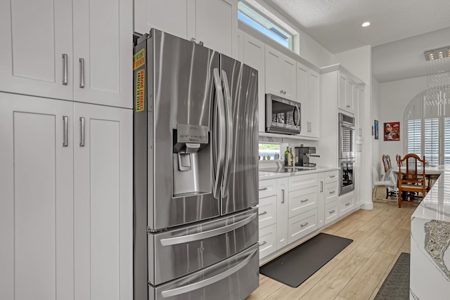 kitchen with light stone counters, recessed lighting, appliances with stainless steel finishes, white cabinets, and light wood finished floors