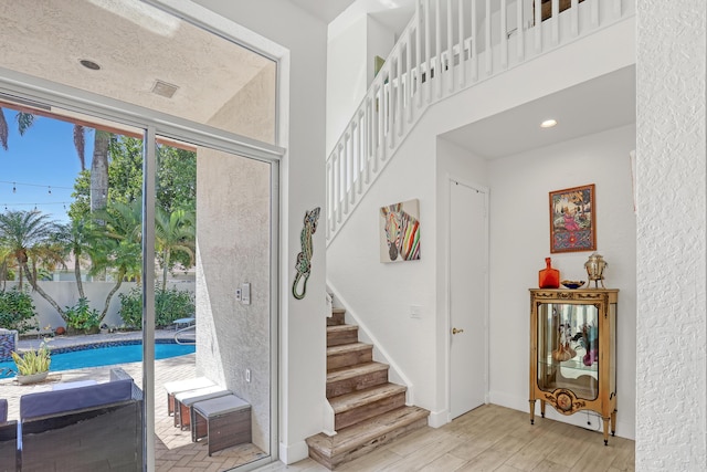 staircase featuring recessed lighting, wood finished floors, and a towering ceiling