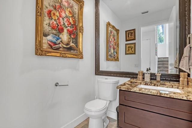 half bath with vanity, wood finished floors, visible vents, baseboards, and toilet