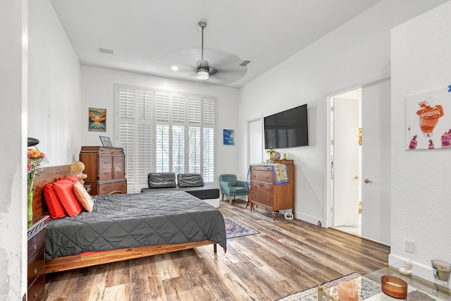 bedroom featuring ceiling fan, visible vents, baseboards, and wood finished floors