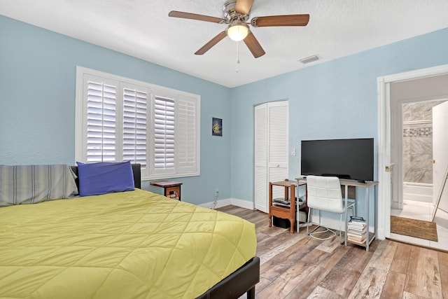 bedroom with visible vents, wood finished floors, a closet, baseboards, and ceiling fan