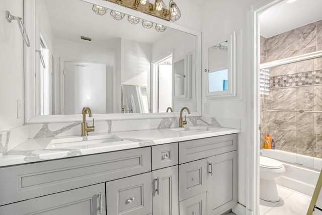 full bathroom with double vanity, enclosed tub / shower combo, toilet, and a sink