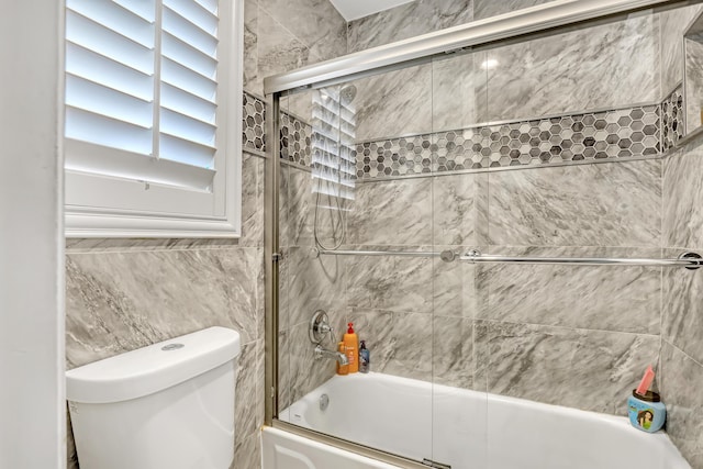 bathroom with combined bath / shower with glass door and toilet