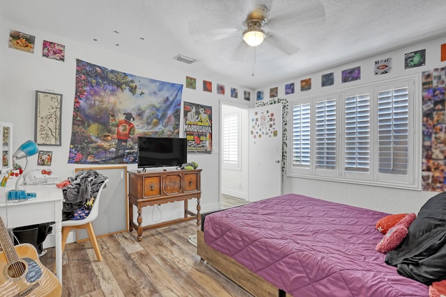 bedroom featuring visible vents, a textured ceiling, ceiling fan, and wood finished floors