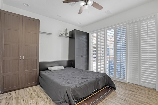 bedroom with light wood finished floors, multiple windows, and a ceiling fan