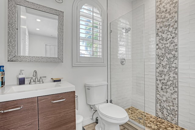 bathroom with a shower stall, toilet, vanity, and baseboards