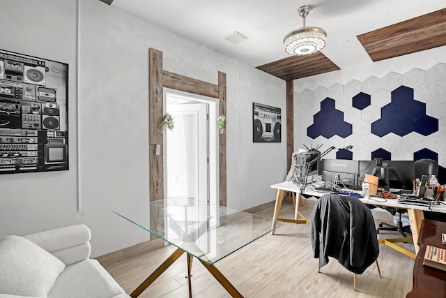 office area featuring visible vents, an accent wall, and wood finished floors