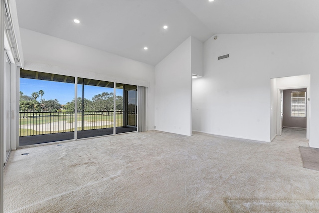 unfurnished living room with light carpet and high vaulted ceiling