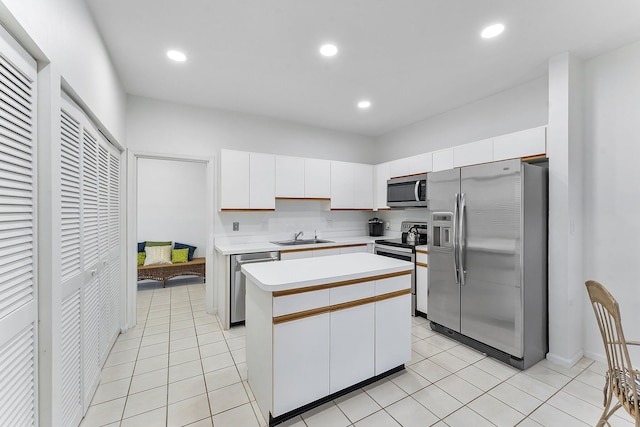 kitchen with appliances with stainless steel finishes, a center island, white cabinetry, and light tile patterned floors