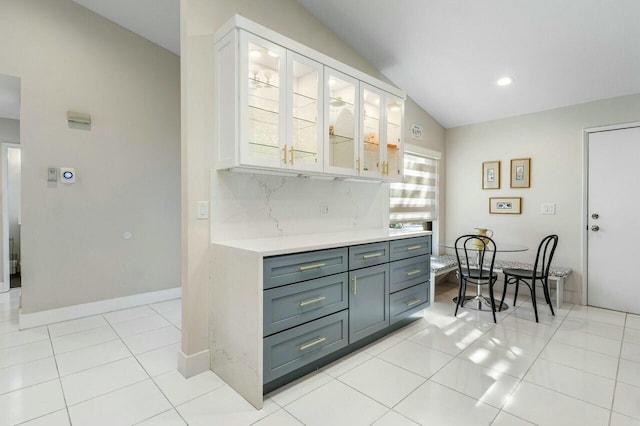 kitchen with white cabinets, decorative backsplash, vaulted ceiling, and a wealth of natural light