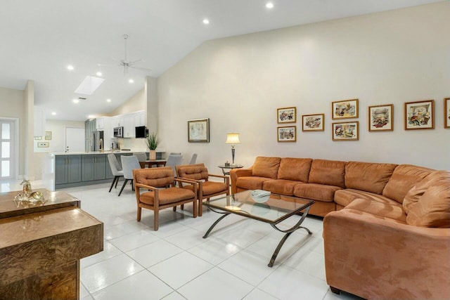 living room featuring ceiling fan, light tile patterned floors, high vaulted ceiling, and a skylight