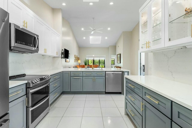 kitchen featuring ceiling fan, stainless steel appliances, kitchen peninsula, decorative backsplash, and white cabinets