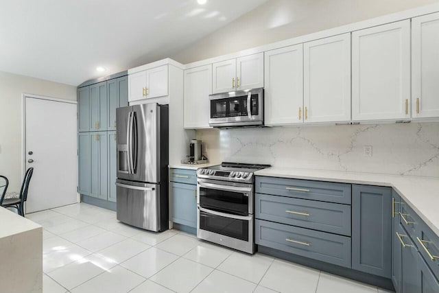 kitchen featuring lofted ceiling, decorative backsplash, light tile patterned floors, appliances with stainless steel finishes, and white cabinetry