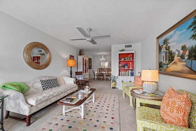 living room with a textured ceiling, ceiling fan with notable chandelier, and light carpet