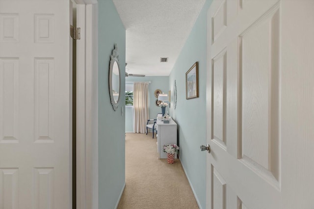 corridor with a textured ceiling and light colored carpet