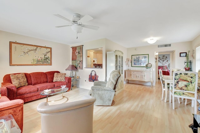 living room featuring ceiling fan, light wood finished floors, and visible vents