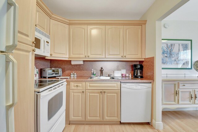 kitchen featuring light wood-type flooring, white appliances, tasteful backsplash, and sink