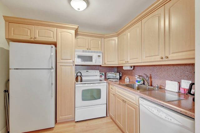 kitchen with white appliances, light countertops, a sink, and light wood finished floors