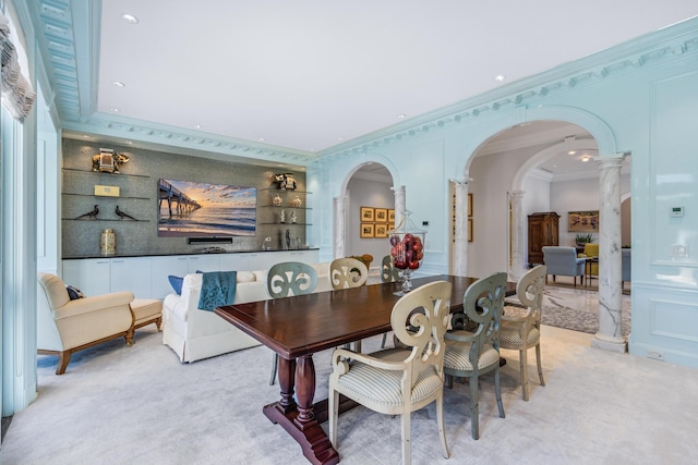 dining room with ornamental molding, arched walkways, light carpet, and a decorative wall