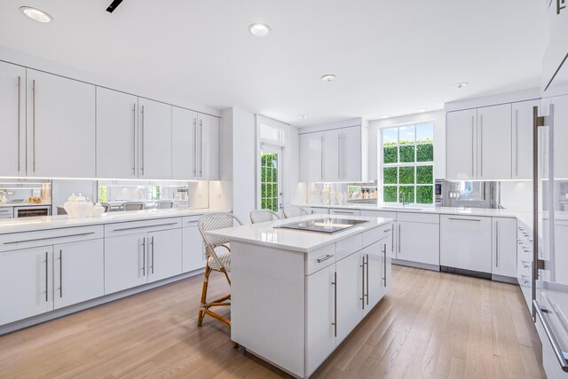 kitchen with tasteful backsplash, a kitchen island, black electric stovetop, light countertops, and white cabinetry