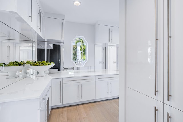 kitchen with light stone counters, recessed lighting, white cabinetry, and light wood-style flooring