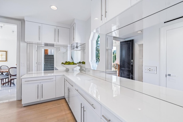 kitchen featuring white cabinetry, light wood-style flooring, and a peninsula