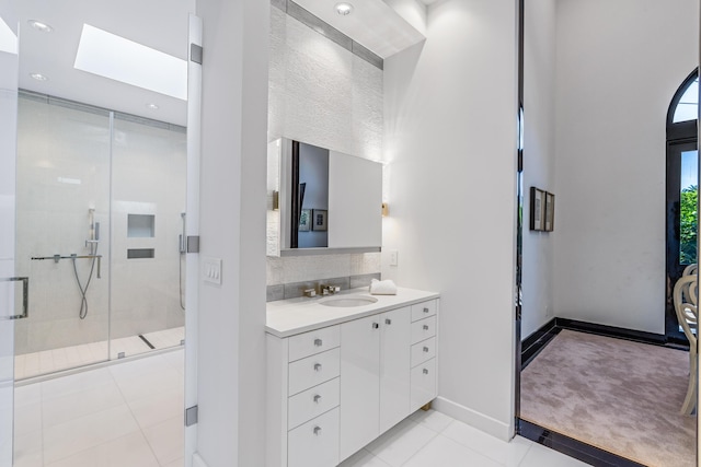 bathroom featuring tasteful backsplash, baseboards, tile patterned flooring, vanity, and a shower stall