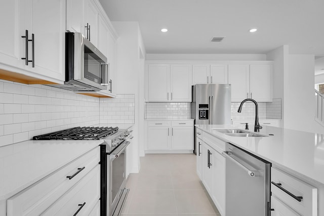 kitchen featuring premium appliances, white cabinetry, sink, and light tile patterned floors