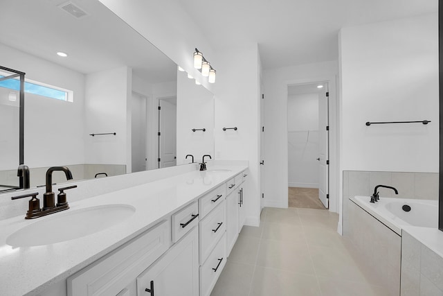 bathroom featuring tile patterned floors, vanity, and a relaxing tiled tub