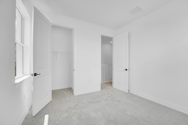 unfurnished bedroom featuring light carpet and a closet