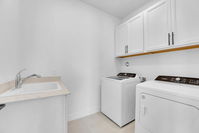 washroom with cabinets, light tile patterned floors, washing machine and clothes dryer, and sink