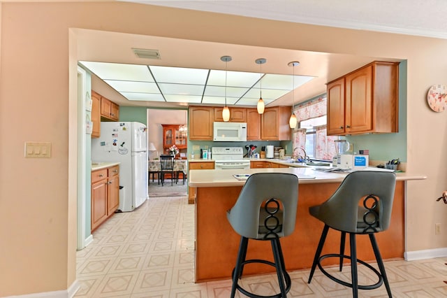 kitchen featuring sink, kitchen peninsula, crown molding, white appliances, and a breakfast bar area