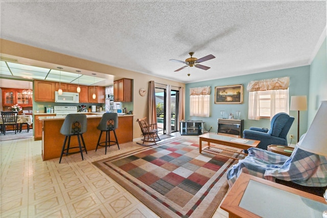 living room with ceiling fan, plenty of natural light, and a textured ceiling