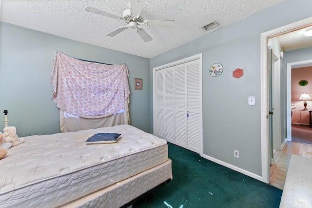 bedroom with a textured ceiling, a closet, dark carpet, and ceiling fan