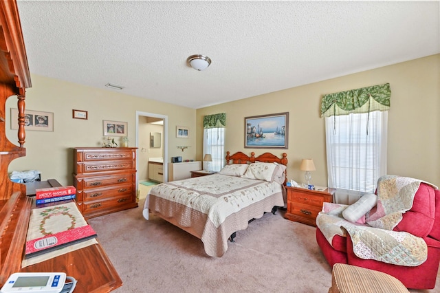 carpeted bedroom featuring a textured ceiling and ensuite bath