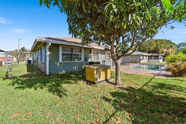 back of house featuring a fenced in pool, a patio area, and a lawn