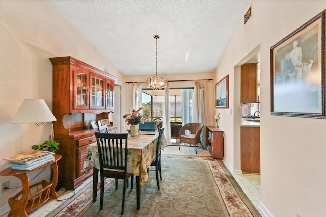 dining room with lofted ceiling, a textured ceiling, and a chandelier