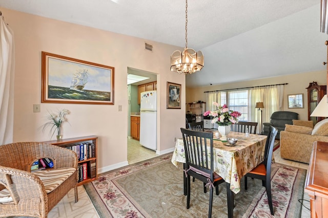 dining room with a notable chandelier, a textured ceiling, and vaulted ceiling