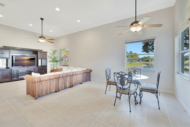 tiled living room with ceiling fan, plenty of natural light, and a water view