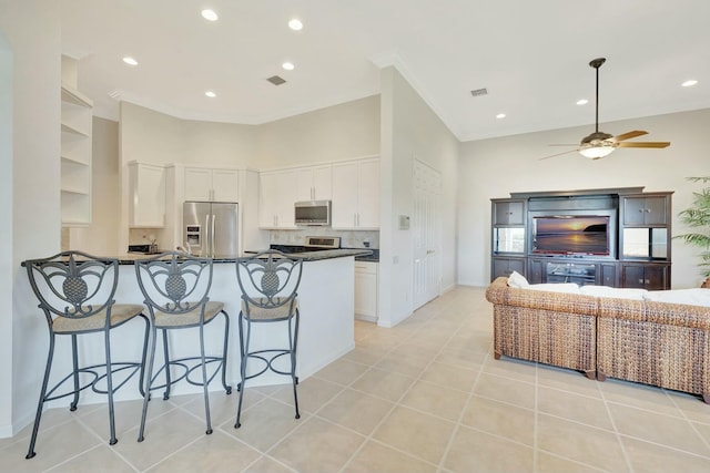 kitchen featuring kitchen peninsula, a breakfast bar, stainless steel appliances, light tile patterned floors, and white cabinetry