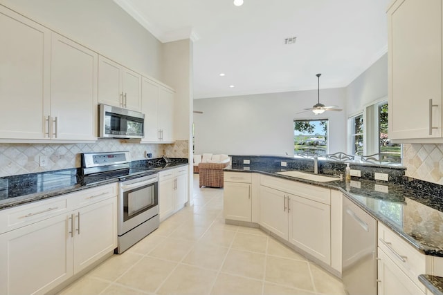 kitchen featuring appliances with stainless steel finishes, ceiling fan, sink, decorative light fixtures, and dark stone countertops