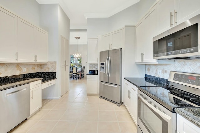 kitchen featuring appliances with stainless steel finishes, white cabinetry, dark stone counters, and light tile patterned flooring