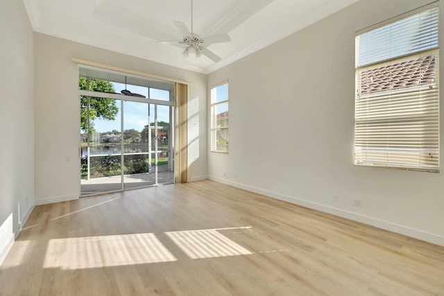 spare room featuring a tray ceiling, ceiling fan, a water view, and light wood-type flooring