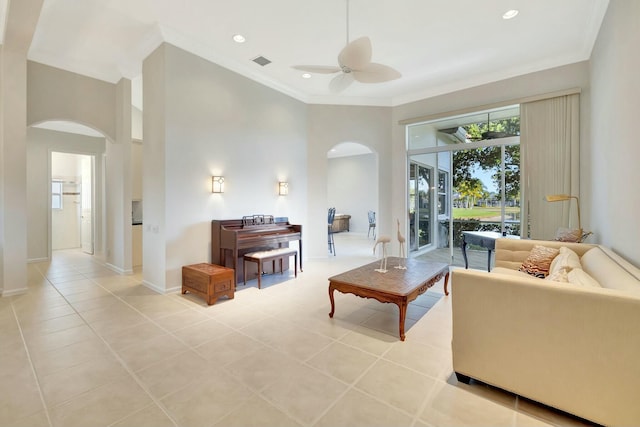 living room with ceiling fan, light tile patterned flooring, ornamental molding, and a high ceiling