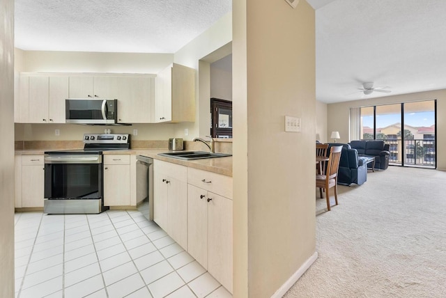 kitchen featuring light carpet, appliances with stainless steel finishes, a textured ceiling, ceiling fan, and sink