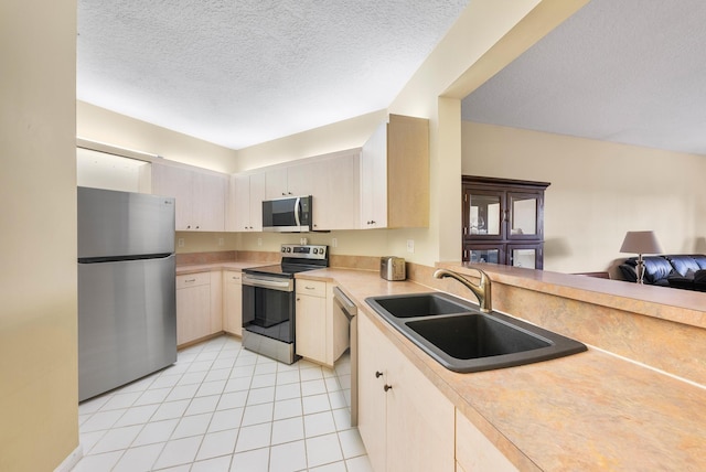 kitchen with sink, light tile patterned floors, a textured ceiling, and appliances with stainless steel finishes