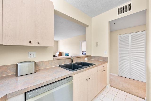 kitchen featuring sink, light tile patterned floors, stainless steel dishwasher, and a textured ceiling