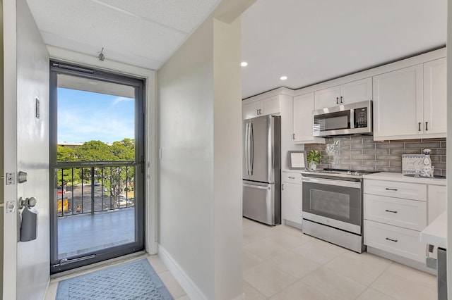 kitchen with backsplash, light tile patterned flooring, white cabinets, and appliances with stainless steel finishes