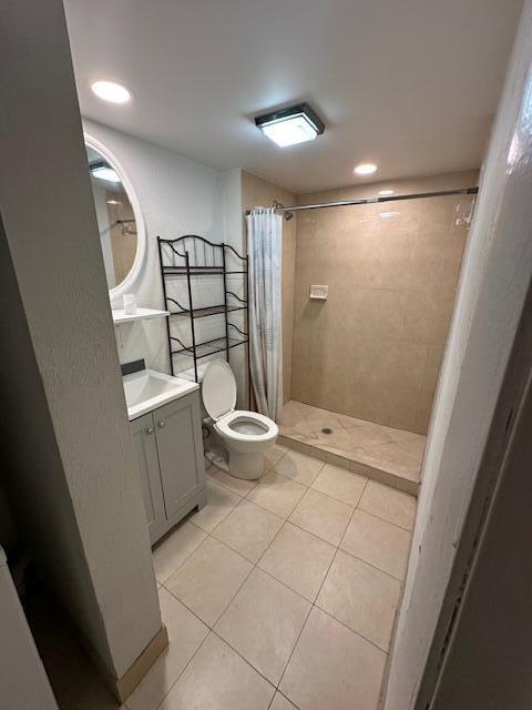 bathroom featuring a shower with shower curtain, tile patterned floors, vanity, and toilet